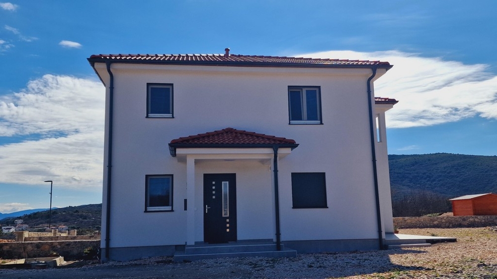 Pohľad spredu na dom so vchodom a červenou strechou