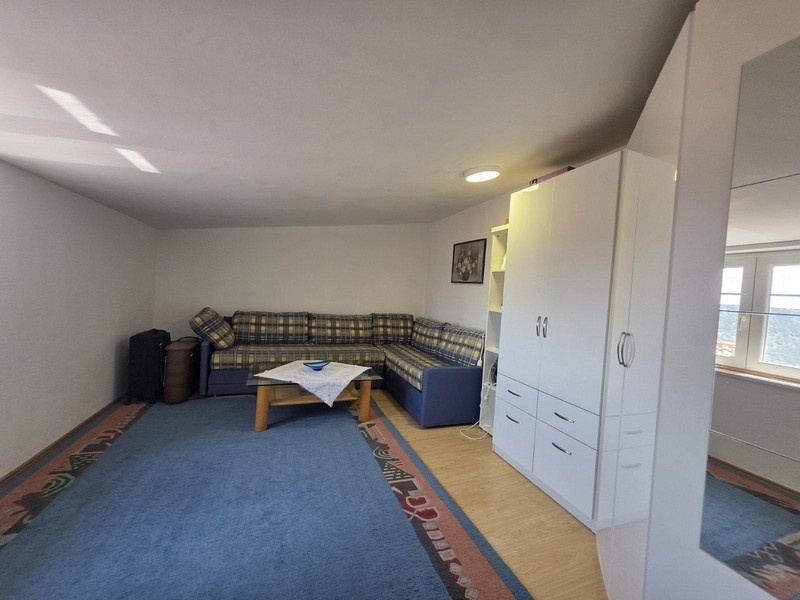 Obývacia izba s rohovou sedačkou, kobercom a skriňou