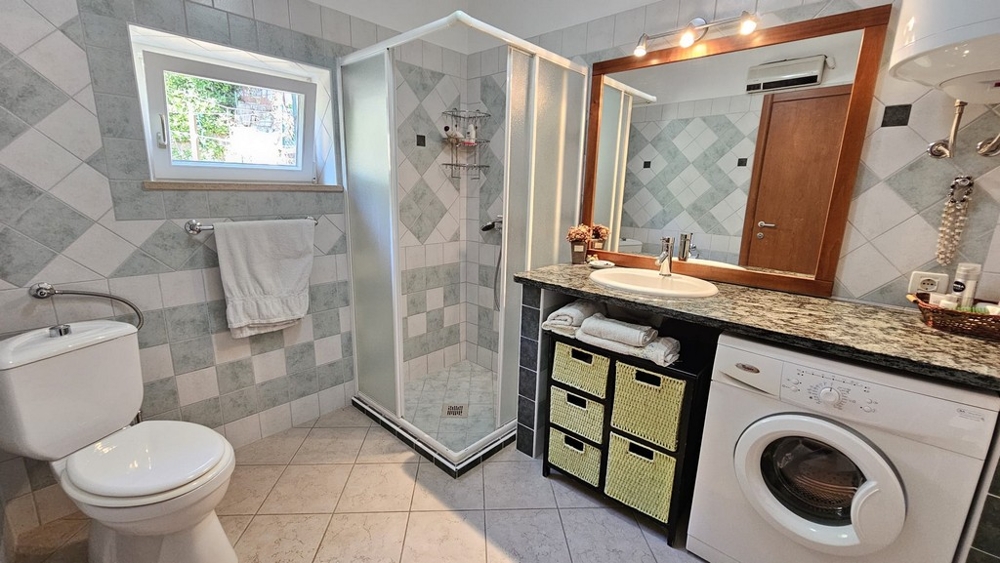 Kúpeľňa so sprchovým kútom, umývadlom a práčkou