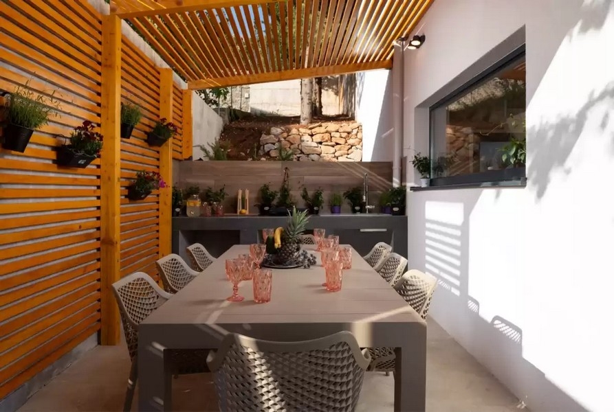 Krytá letná kuchyňa s jedálenským stolom a pergolou