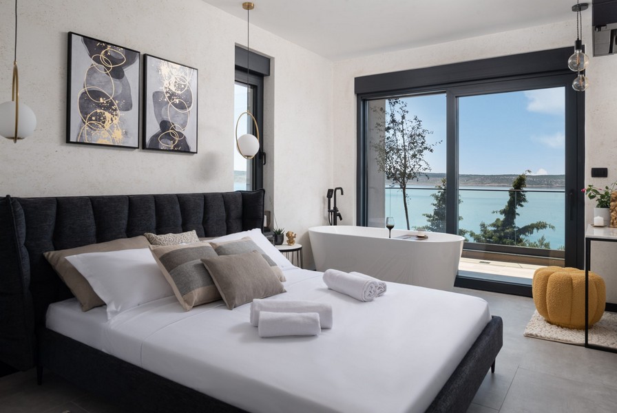 Spálňa s manželskou posteľou, voľne stojacou vaňou a výhľadom na more