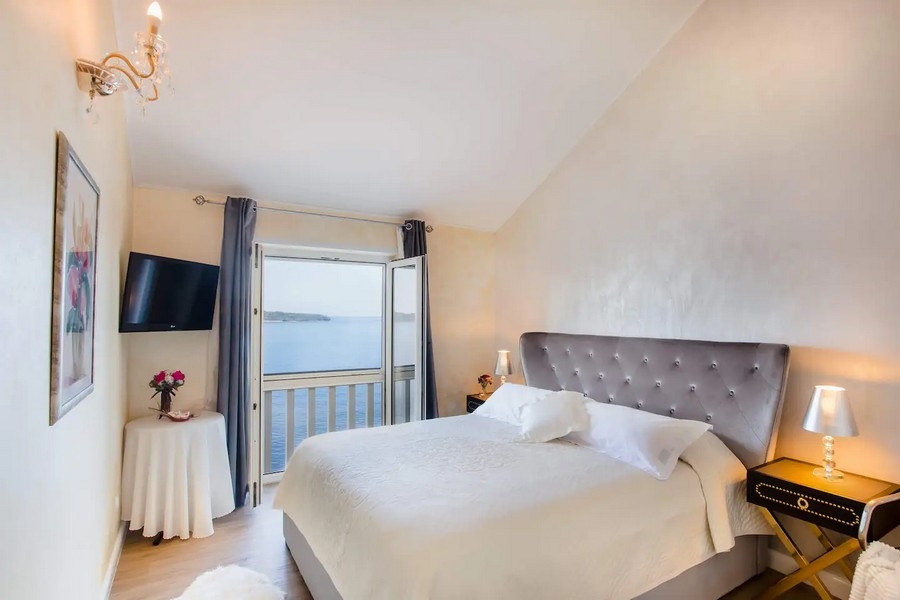 Svetlá spálňa s manželskou posteľou a balkónom s výhľadom na more