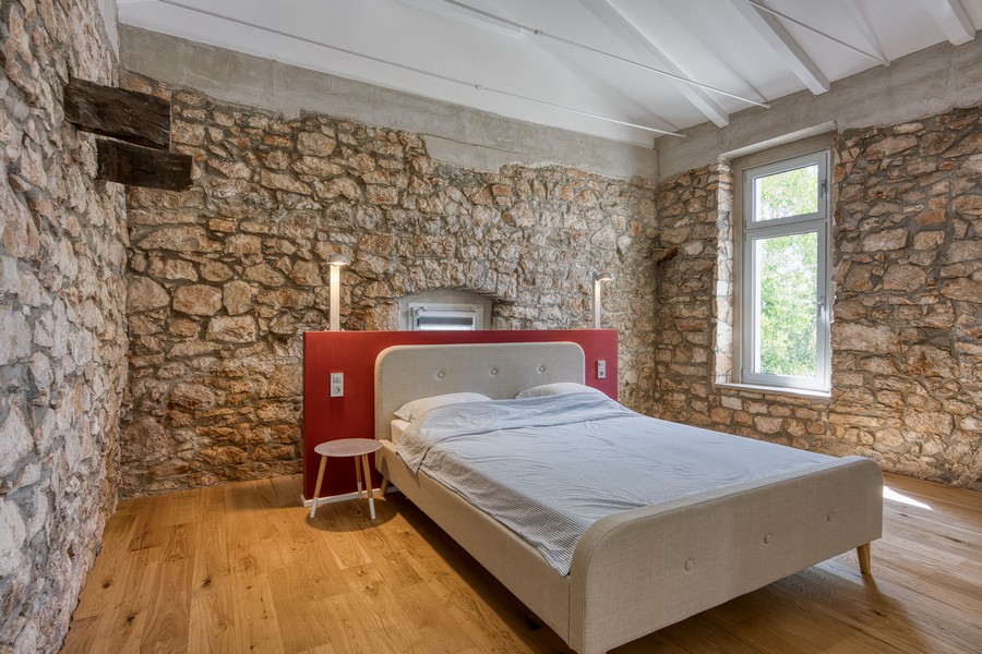 Spálňa so stenami z prírodného kameňa a drevenou podlahou