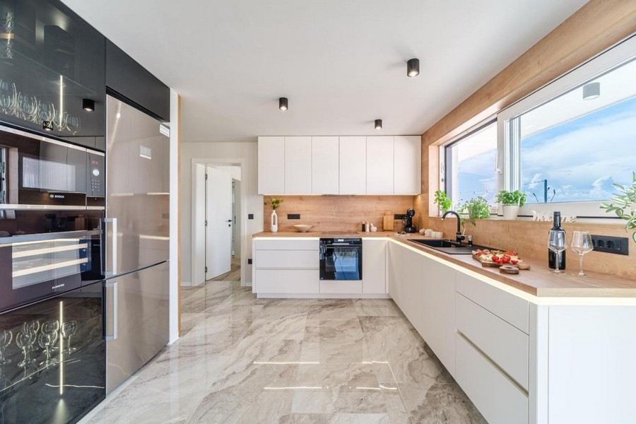 Svetlá zariadená kuchyňa s modernými spotrebičmi a mramorovými obkladmi