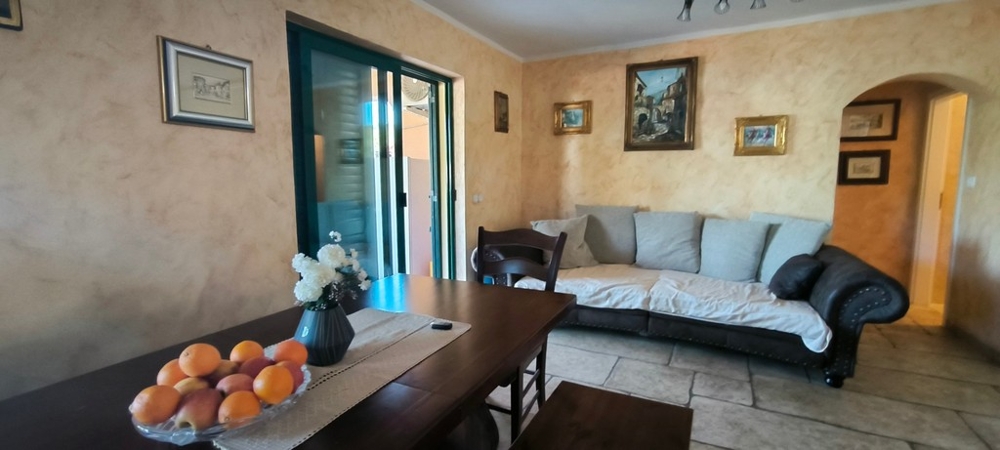 Obývacia izba s pohovkou, stolom a vstupom na terasu