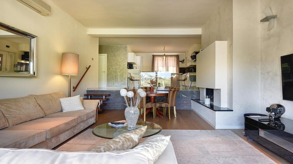 Svetlá obývacia izba s pohovkou, krbom a priľahlým jedálenským kútom