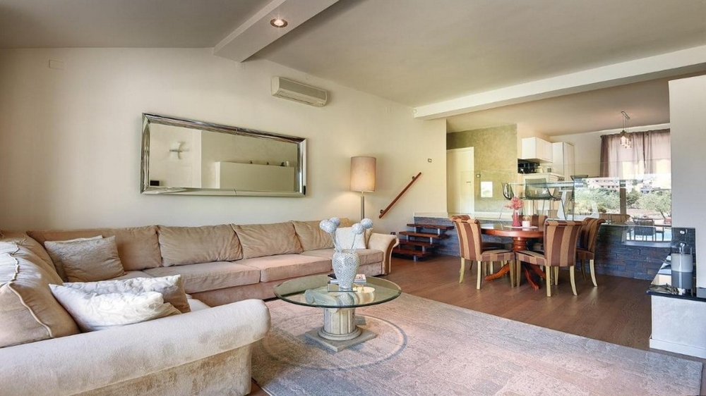 Útulný obývací priestor s rohovou pohovkou, zrkadlom a jedálenským kútom