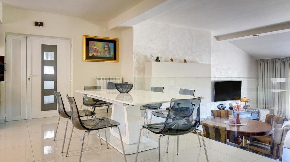 Moderný jedálenský kút s bielym stolom a skleneným zábradlím