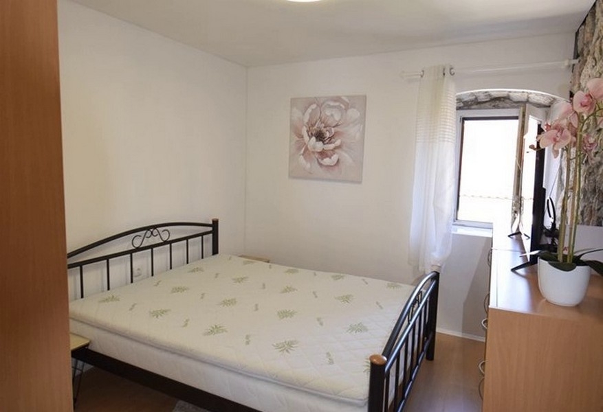 Spálňa s manželskou posteľou a kamennou stenou