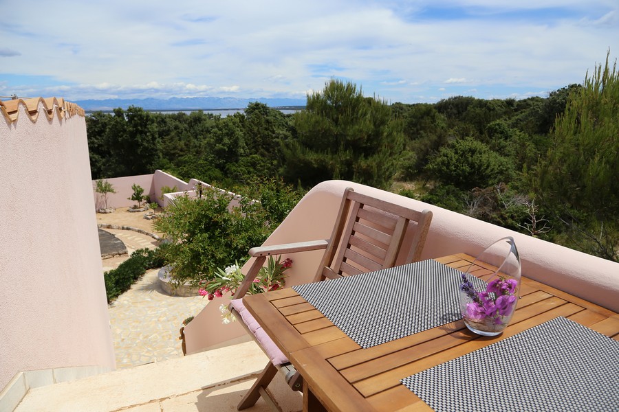 Terasa s dreveným stolom a stoličkami, výhľad do zelene a na more