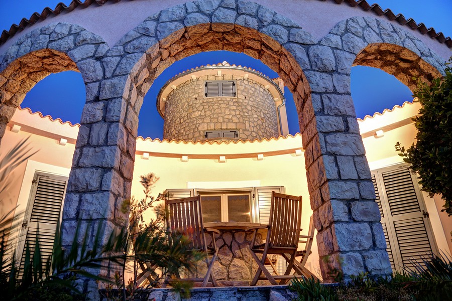 Kamenné arkády a okrúhla veža s v noci osvetlenou terasou