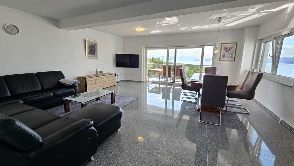 Obývacia izba s veľkou pohovkou a výhľadom na terasu