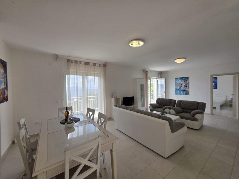 Obývacia izba s pohovkou a jedálenským kútom, výhľad na more