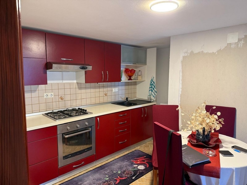 Kuchyňa s červeným vstavaným nábytkom a jedálenským kútom