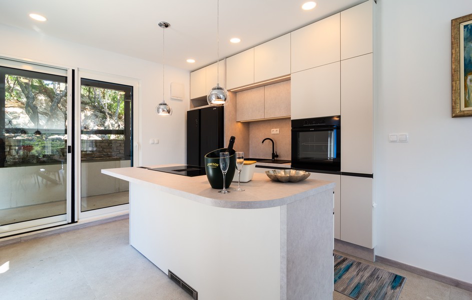 Moderne vybavená kuchyňa s ostrovčekom na varenie a vstupom na terasu