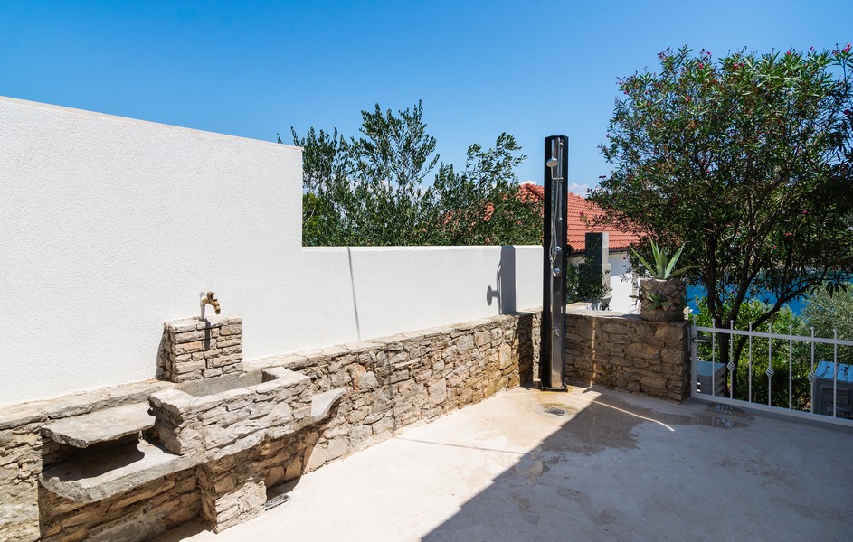 Vonkajší priestor s kamennou lavicou, umývadlom a vonkajšou sprchou