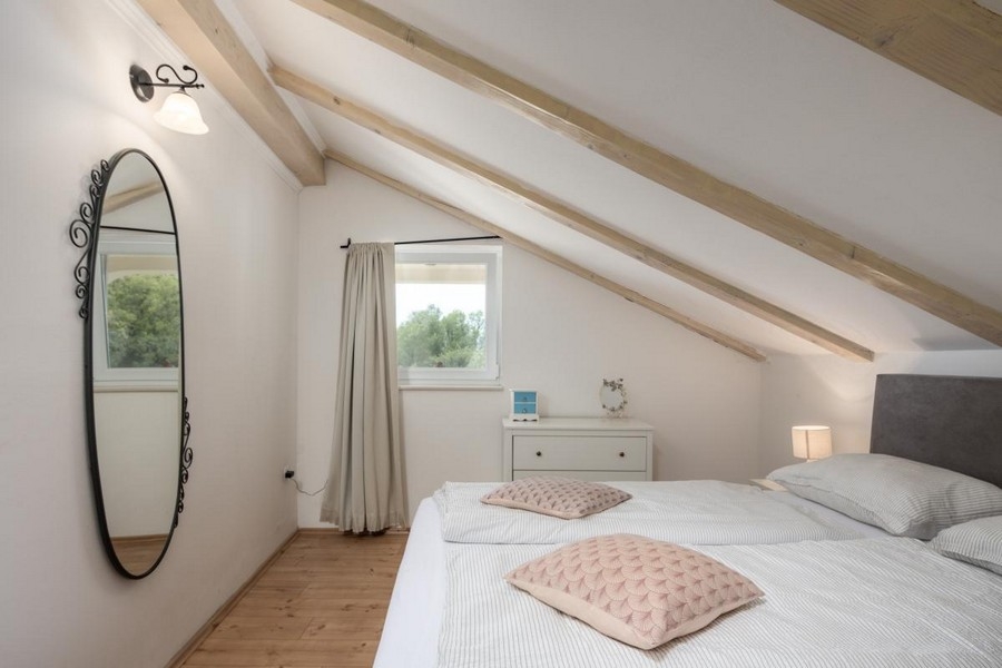 Útulná podkrovná spálňa s drevenými trámami