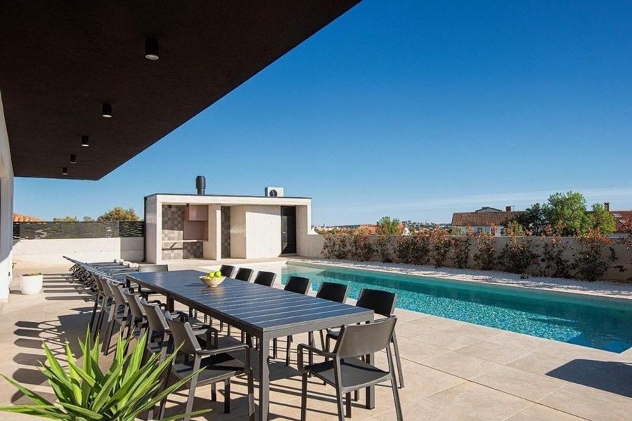 Terasa s veľkým jedálenským stolom a výhľadom na bazén