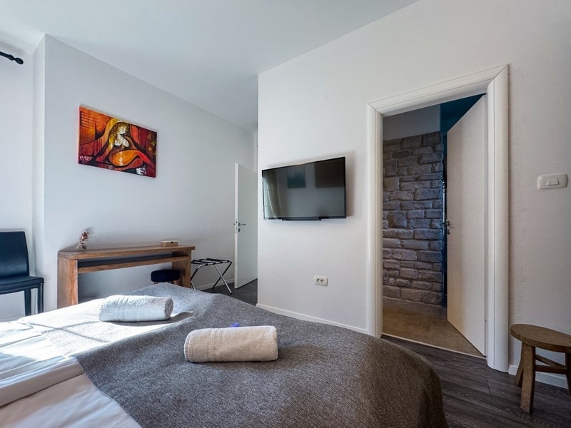 Svetlá spálňa s TV a detailmi kamennej steny