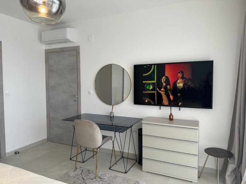 Moderne zariadená spálňa s písacím stolom, zrkadlom a televíziou