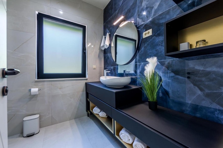Kúpeľňa s modrou mramorovou stenou a okrúhlym zrkadlom