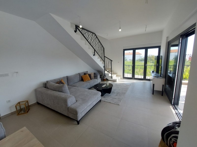 Svetlý obývací priestor s pohovkou a schodiskom