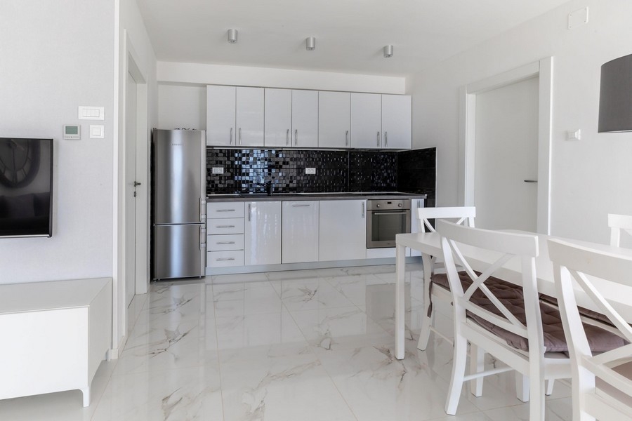 Moderná kuchyňa s bielou vybavenou kuchyňou a jedálenským kútom