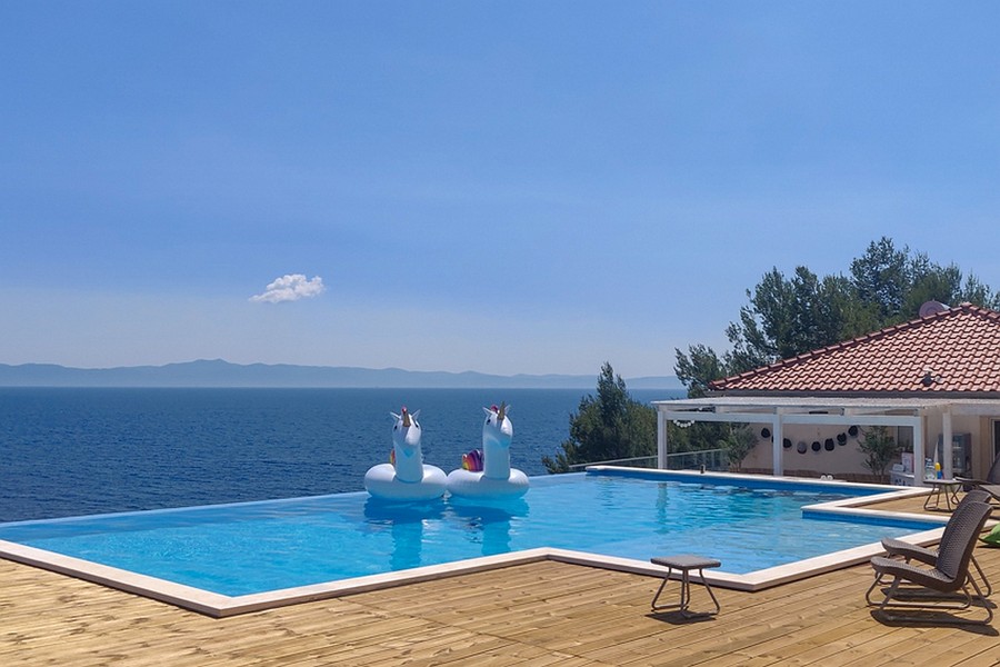 Nekonečný bazén s výhľadom na more a priestrannou drevenou terasou