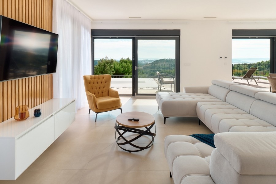 Otvorený obývací priestor s oknami od podlahy až po strop a prístupom na terasu