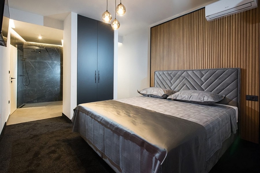 Spálňa s drevenými panelovými stenami a integrovaným sprchovacím kútom