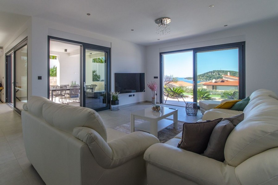 Svetlý obývací priestor s veľkým preskleným priečelím a výhľadom na more