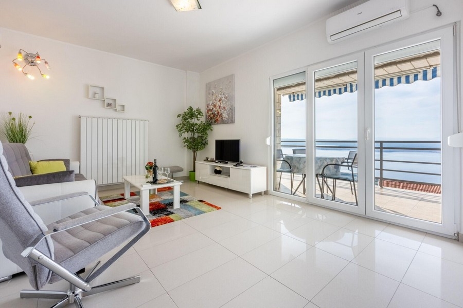 Obývacia izba so vstupom na balkón a výhľadom na more