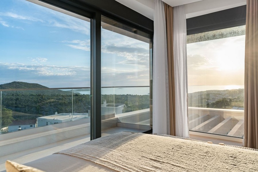 Spálňa s oknami od podlahy až po strop a panoramatickým výhľadom na more