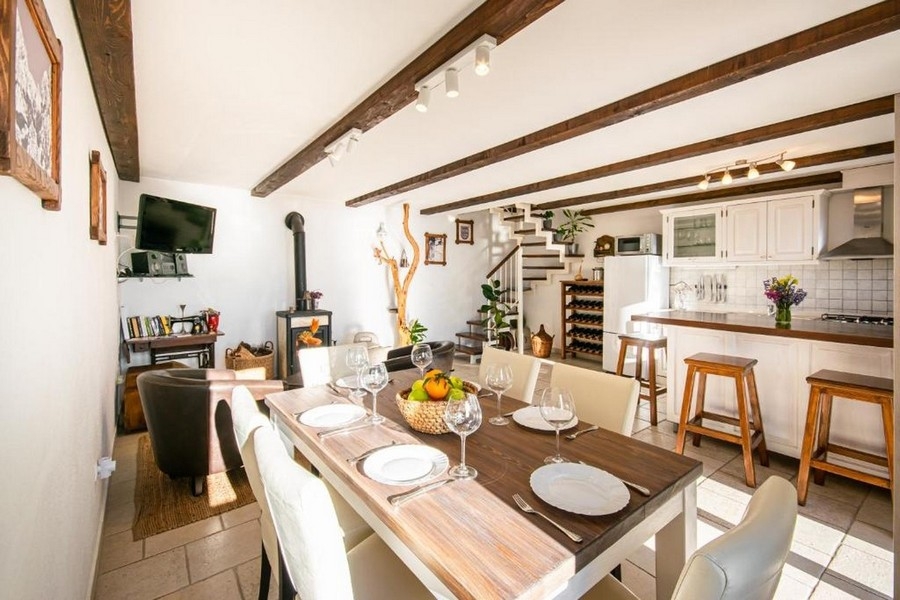 Obývacia časť s drevenými trámami, krbom a kuchyňou