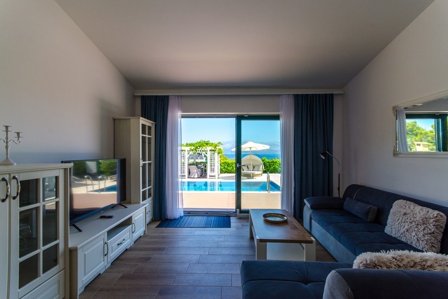 Obývacia izba s prístupom na terasu a výhľadom na bazén