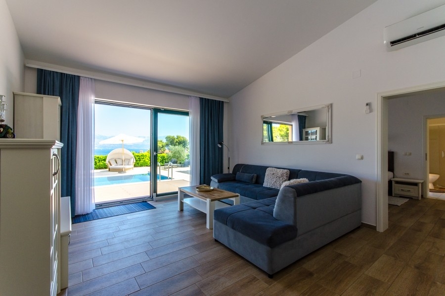 Obývacia izba s pohovkou a dverami na terasu k bazénu