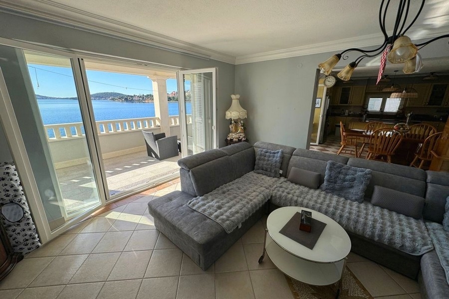 Svetlý obývací priestor s veľkými oknami a výhľadom na more