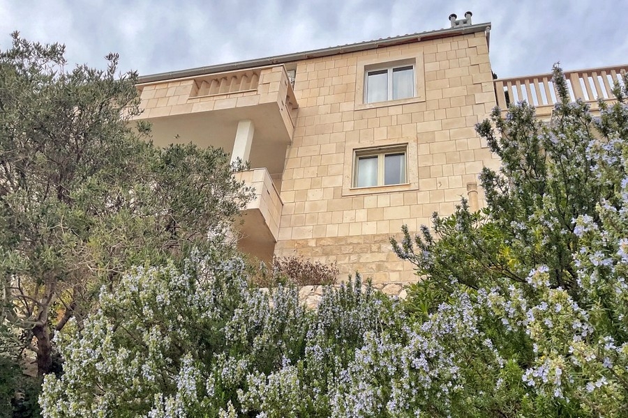 Fasáda domu z prírodného kameňa s balkónom a záhradou