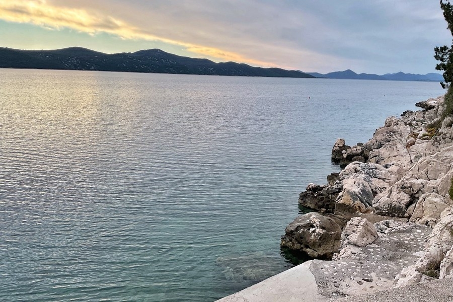 Skalnaté pobrežie a krištáľovo čisté more pred budovou