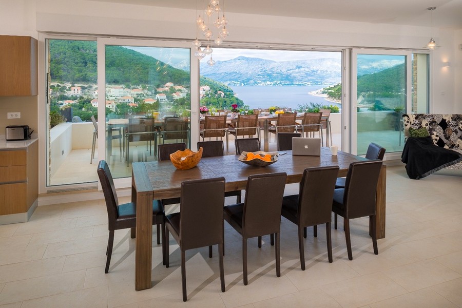 Obývacia izba s veľkým jedálenským stolom a panoramatickými oknami s výhľadom na more