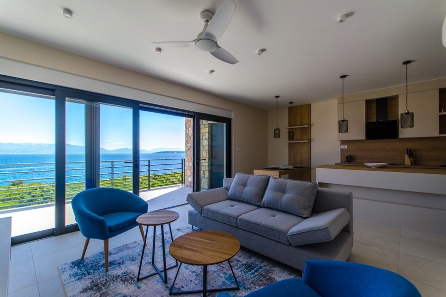 Obývacia izba s výhľadom na more a veľkým oknom v modernom apartmáne