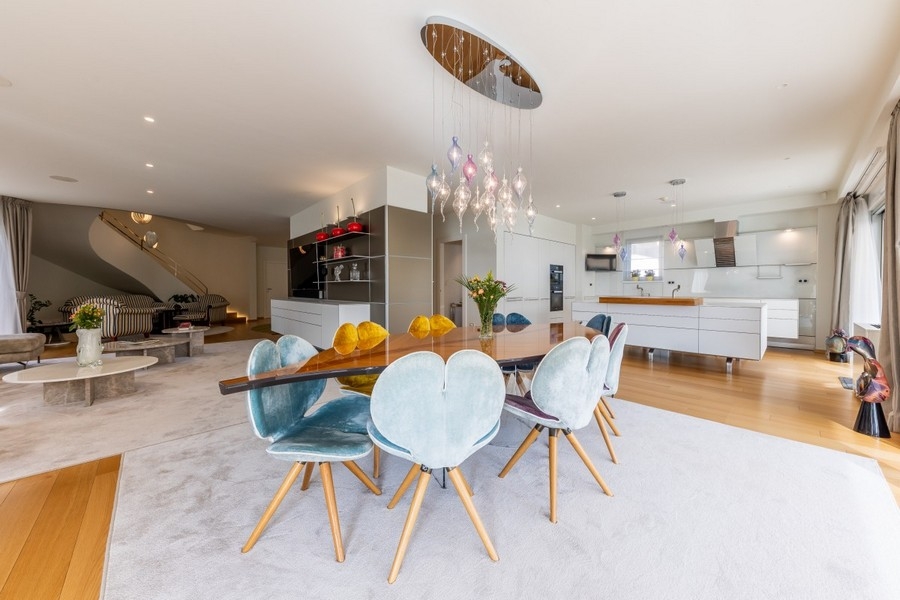 Otvorený jedálenský kút s dizajnovým osvetlením a modernou kuchyňou