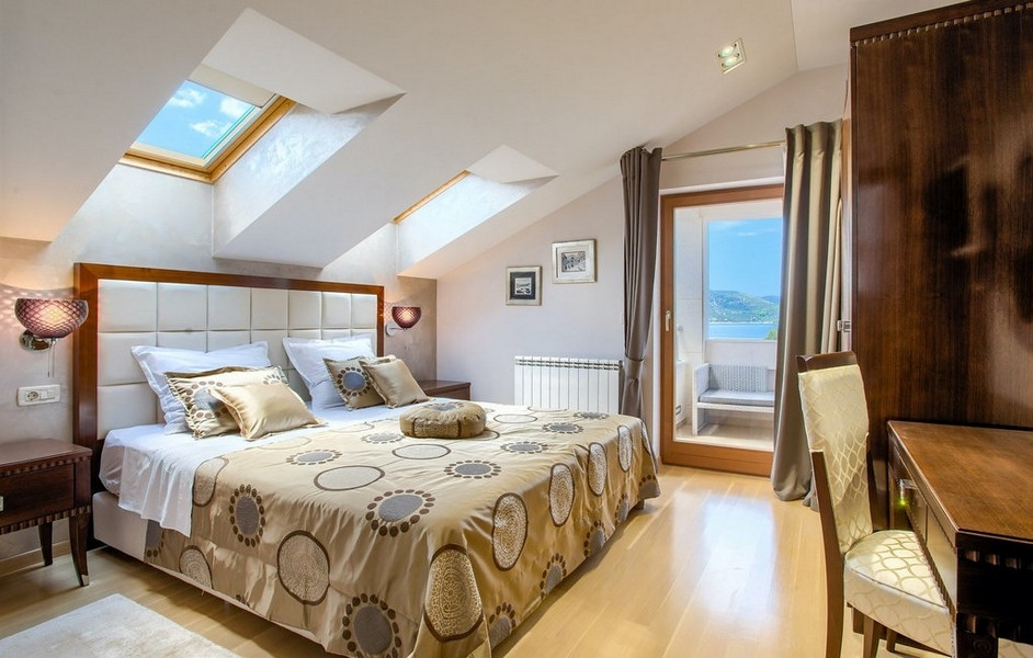 Spálňa so šikmými stropmi a prístupom na balkón s výhľadom na more