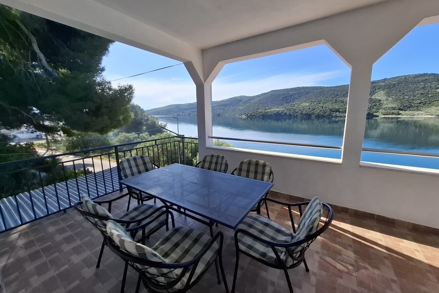 Krytý vonkajší priestor s jedálenským stolom a výhľadom na more