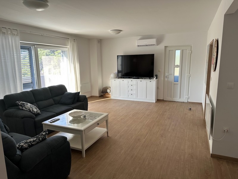 Obývacia izba s pohovkou, TV a prístupom na balkón s moderným zariadením