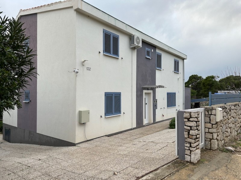 Fasáda domu so vstupným priestorom a parkovacím miestom na oplotenom pozemku v Chorvátsku