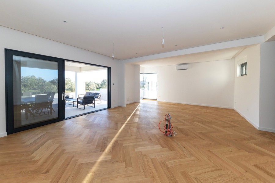 Otvorený obývací priestor s veľkými oknami a vstupom na terasu