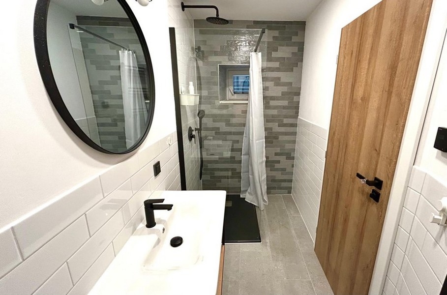 Kúpeľňa so sprchovacím kútom na úrovni podlahy a moderným vybavením
