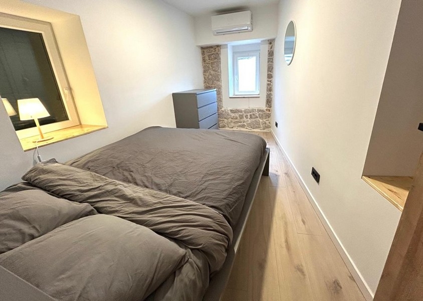 Spálňa s manželskou posteľou a viditeľnou stenou z prírodného kameňa