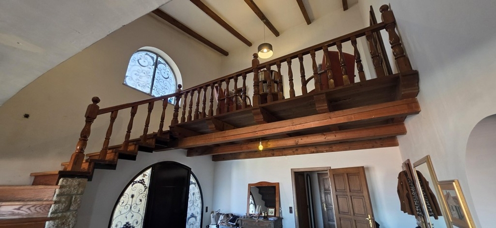 Obývacia izba s krbom, odhalenými drevenými trámami a galériou